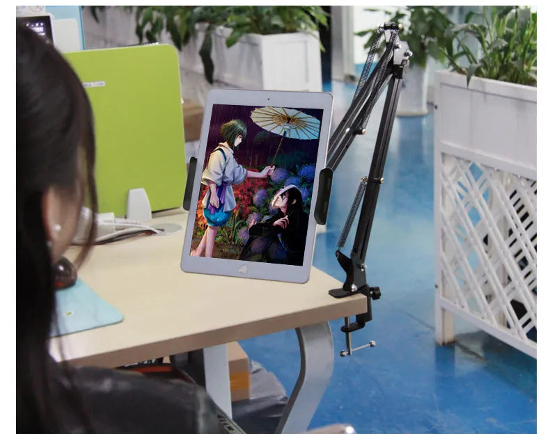 Black adjustable phone tablet stand with 360-degree rotation on wooden table