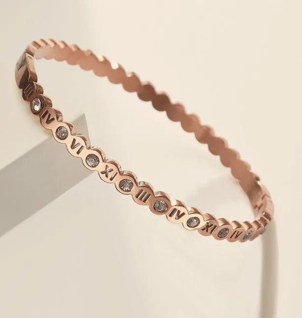 Adjustable titanium steel fashion bracelet with number charms in a choice of gold, rose gold, or steel colour.