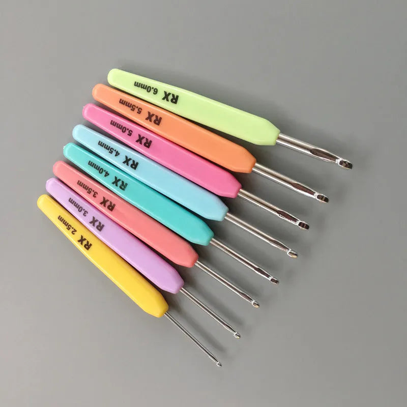 Set of 16 crochet hooks in various sizes with two handle types, laid next to a grey PU storage bag.
