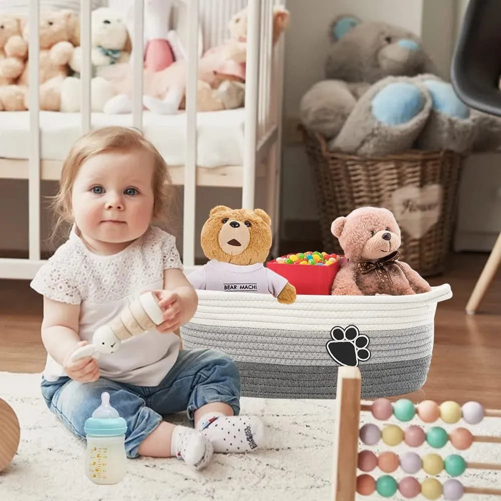 Light beige handmade woven cotton rope storage basket with wooden handle on a table.