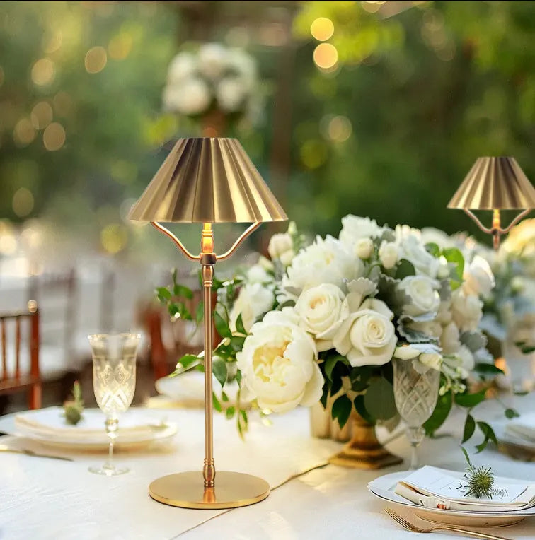 Gold alloy desk lamp with a fabric lampshade on a wooden table