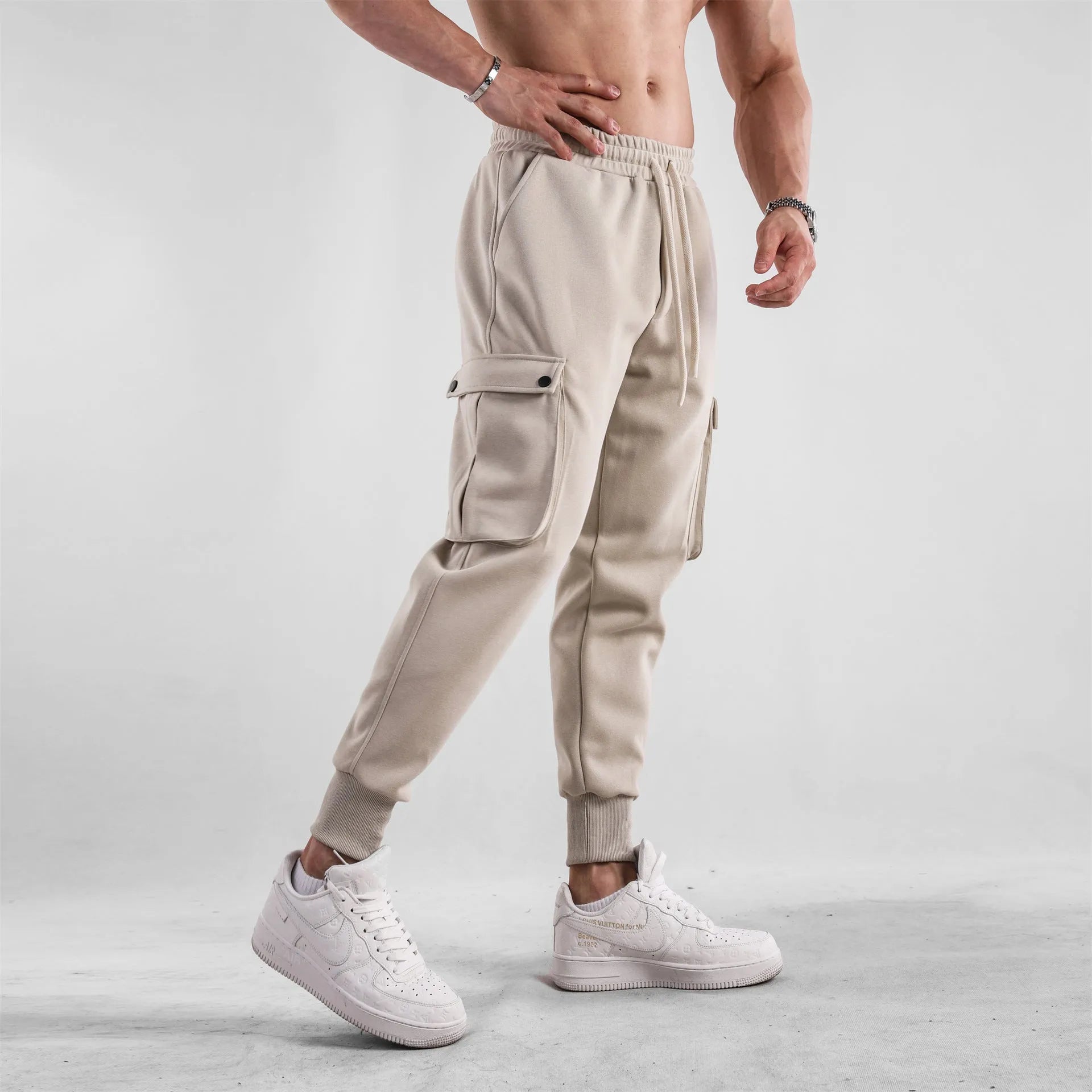 Men's loose light grey cotton sports trousers with ankle ties and multiple pockets laid flat.