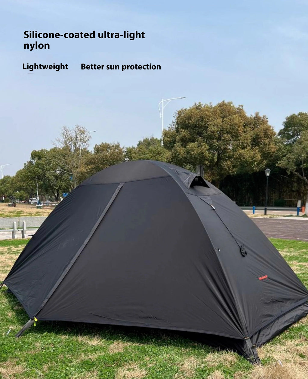 Red single person dome tent with aluminium poles pitched outdoors, showing double-layer construction.