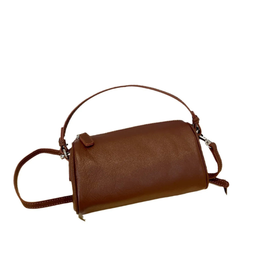 Vegetable tanned leather crossbody phone bag in cylindrical shape on a single adjustable strap.