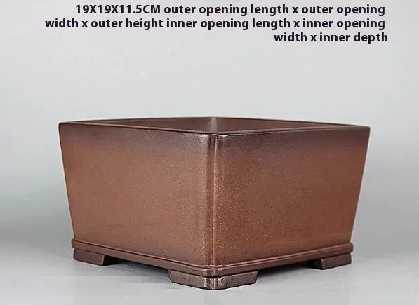 Handmade brown antique flower pot made from purple clay on a wooden surface.