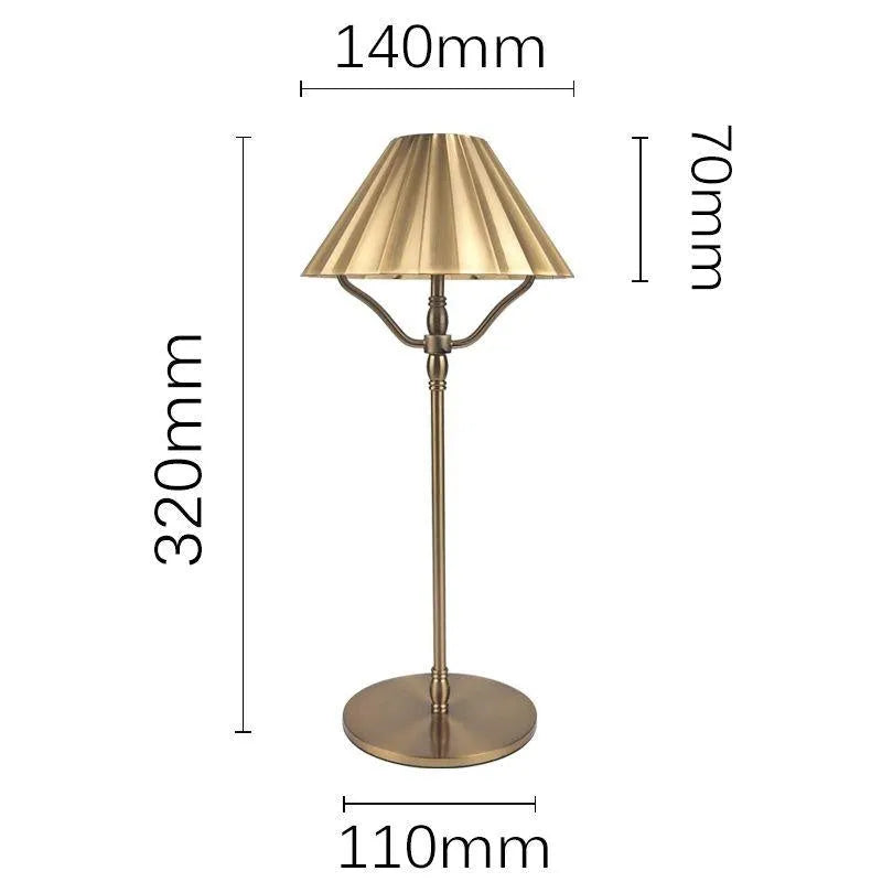 Gold alloy desk lamp with a fabric lampshade on a wooden table