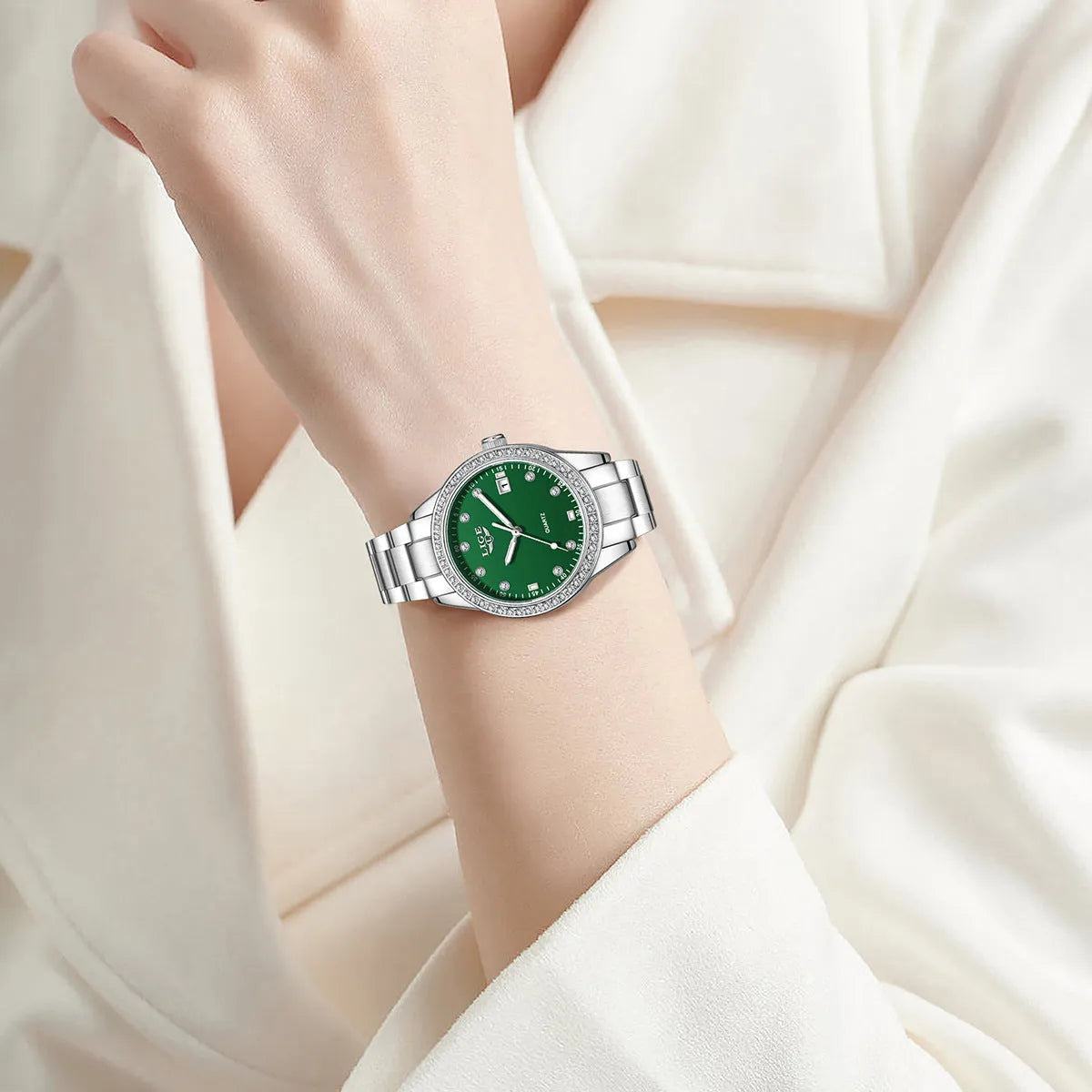 Silver fashion watch with diamond-encrusted round dial and luminous hands on a stainless steel strap.