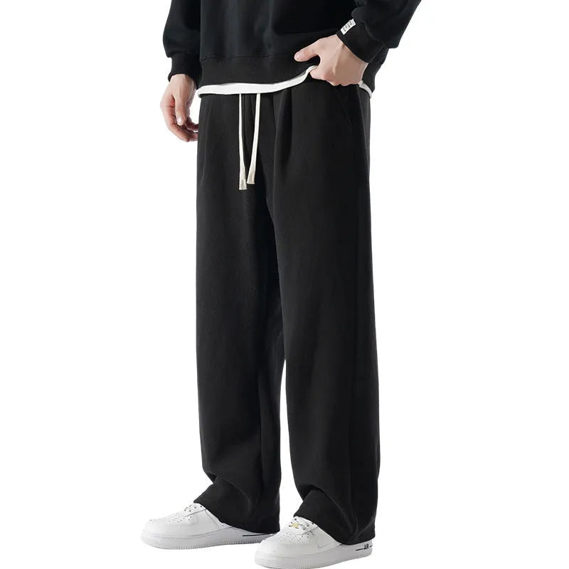 Men's apricot fleece-lined loose-fit sports casual trousers with elastic waist on a hanger.