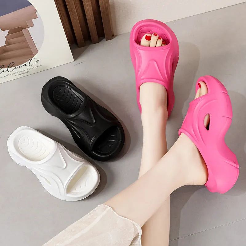 Women's thick-soled EVA slippers in rose red colour on a sandy beach background.