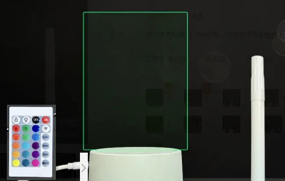 3D acrylic message board LED lamp lit up on a desk with remote control and marker pen.
