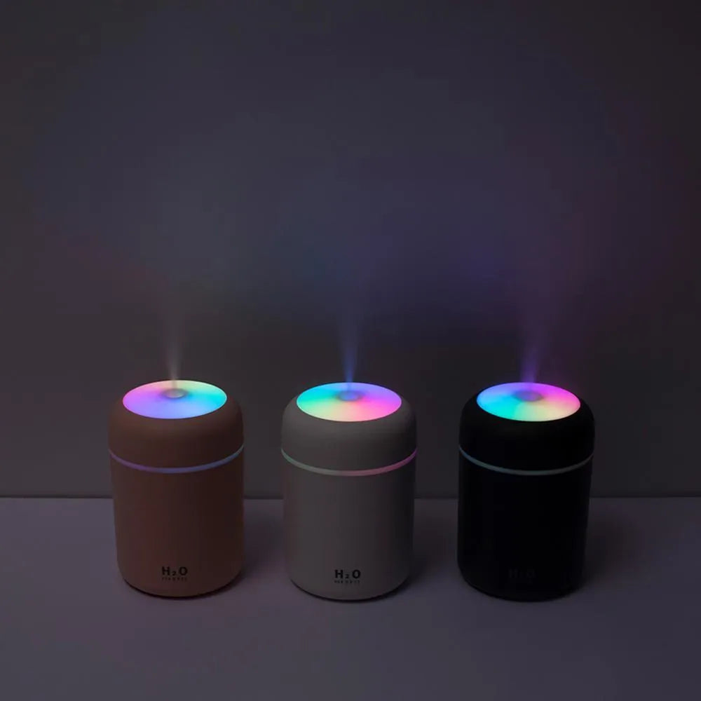 Pink USB portable humidifier with LED lights and water tank on wooden desk
