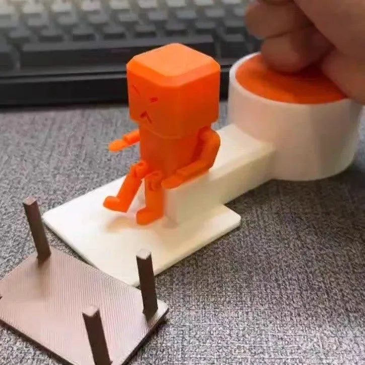Orange plastic Take a Shot vent decompression toy with a rotating table on a desk.
