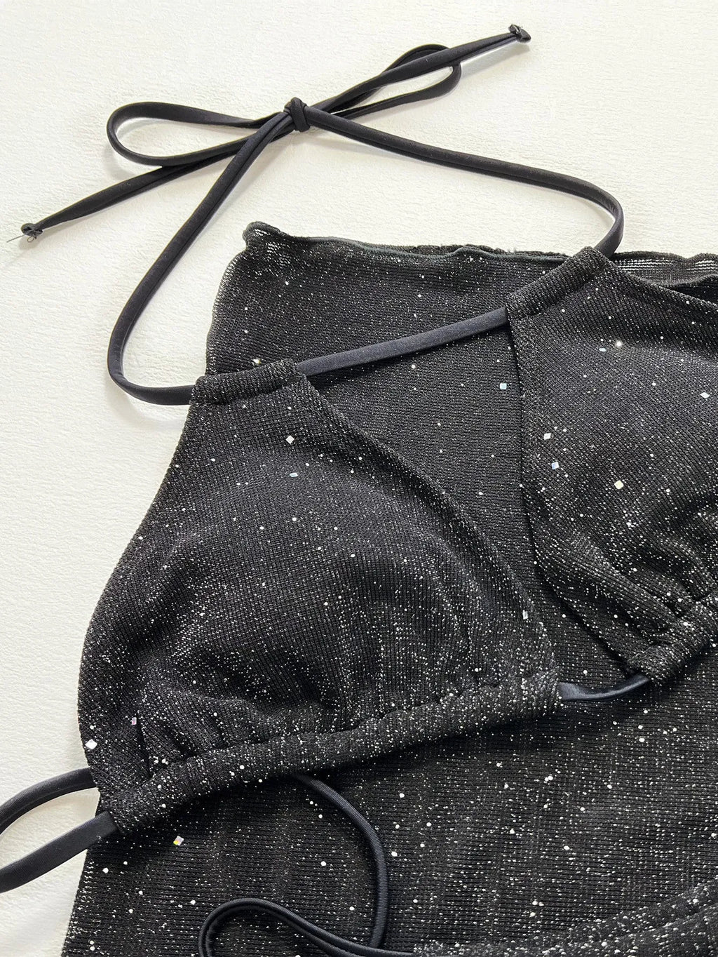 Black three-piece bikini swimsuit set with a top and shorts on a mannequin.