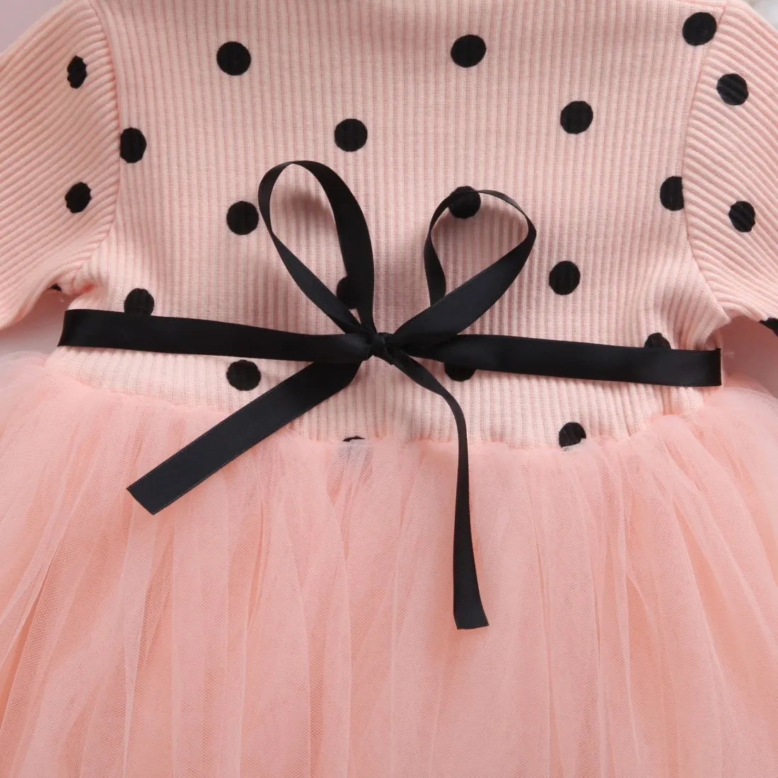 Baby girl wearing a long sleeve black tutu dress with lace detail, suitable for a party or casual wear.