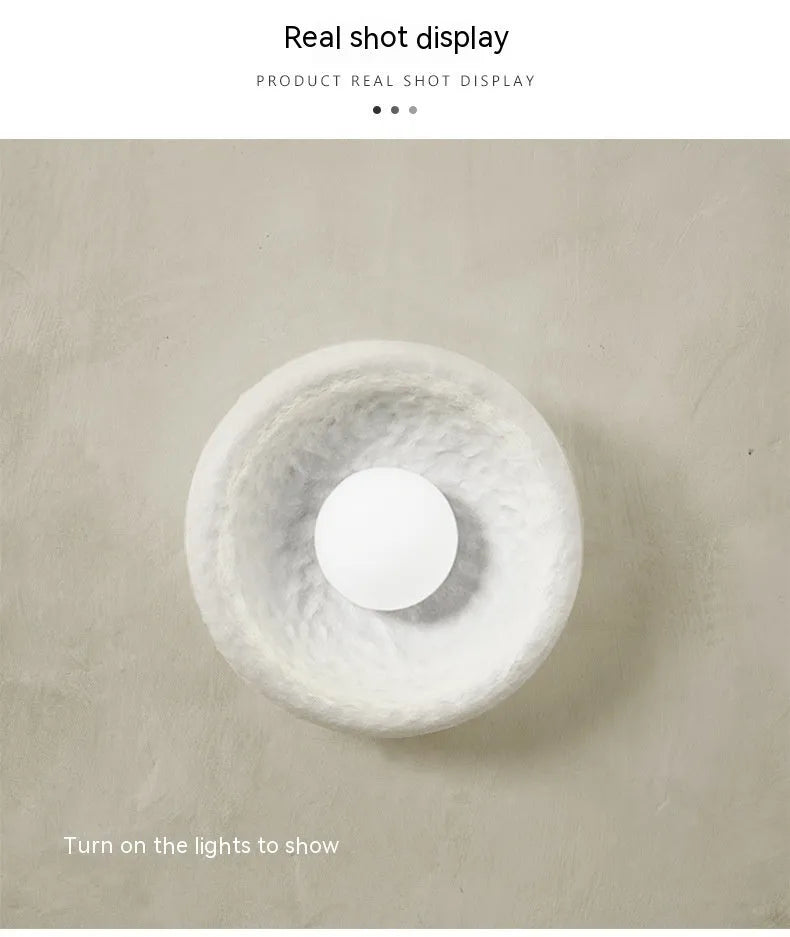 Japanese modern simple wall lamp with white resin shade in three size options on a plain wall.