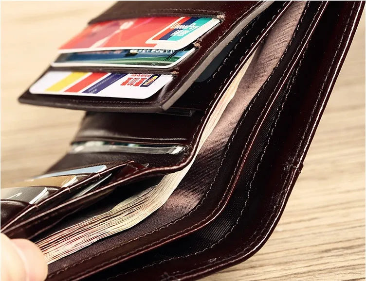 Men's black leather wallet open to show internal card slots, coin pocket, and document sleeve.