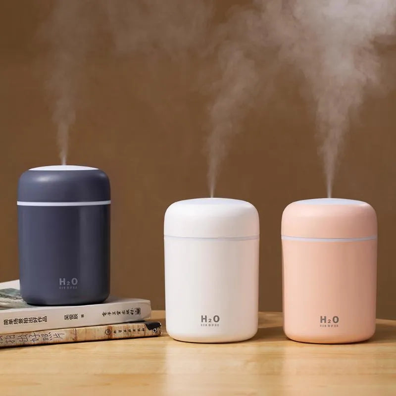 Pink USB portable humidifier with LED lights and water tank on wooden desk