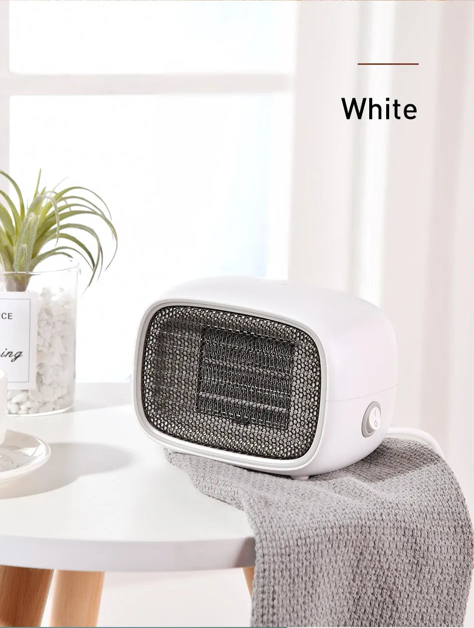 Mini green desktop heater with metal grille showing compact size on a wooden desk