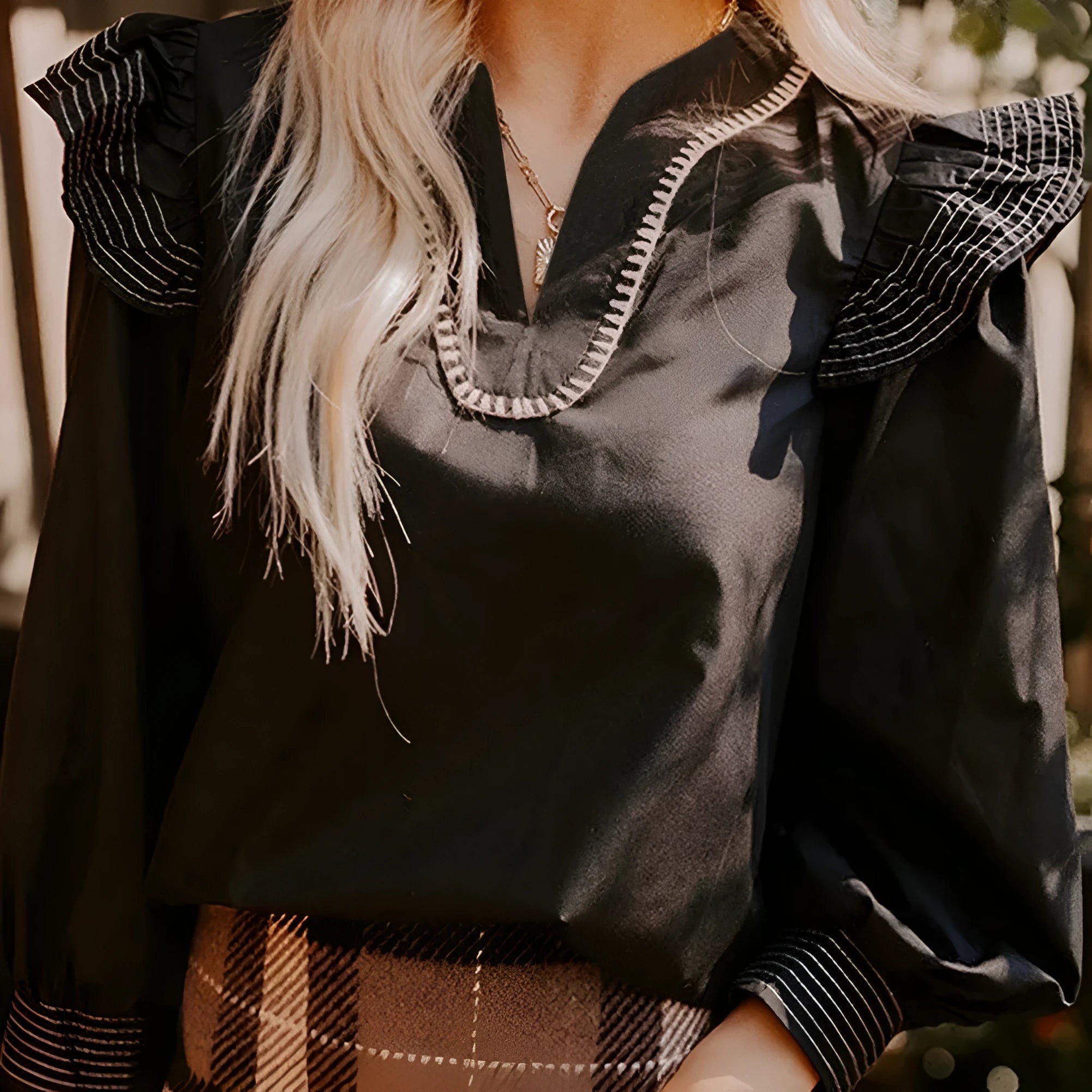 Black V-neck blouse with contrast stitching and ruffle long sleeves on hanger