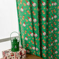 Green festive curtain with printed cartoon snowman and angel pattern.