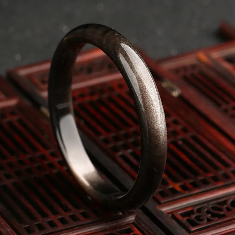 Natural silver stone cat's eye bracelet with geometric ethnic design on a wrist.