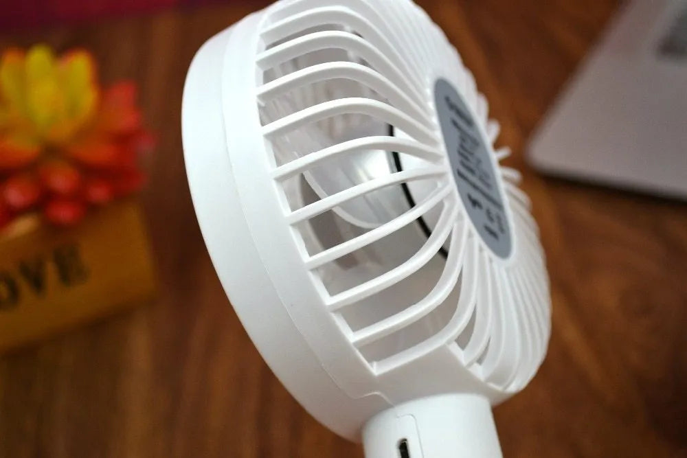 White ORICO FH1 portable USB desk and handheld fan with rechargeable battery on a wooden table.