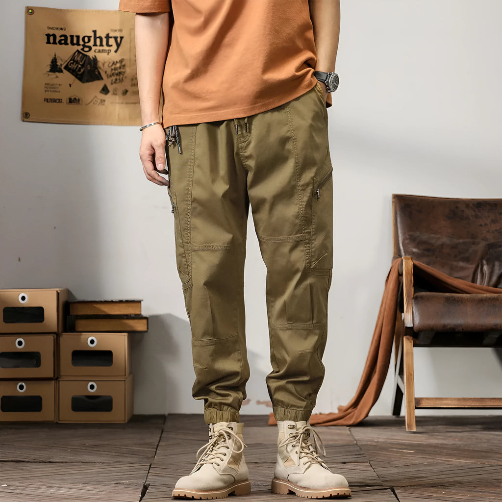 Men's loose cotton harem pants in khaki with a tapered ankle opening and zip fly.