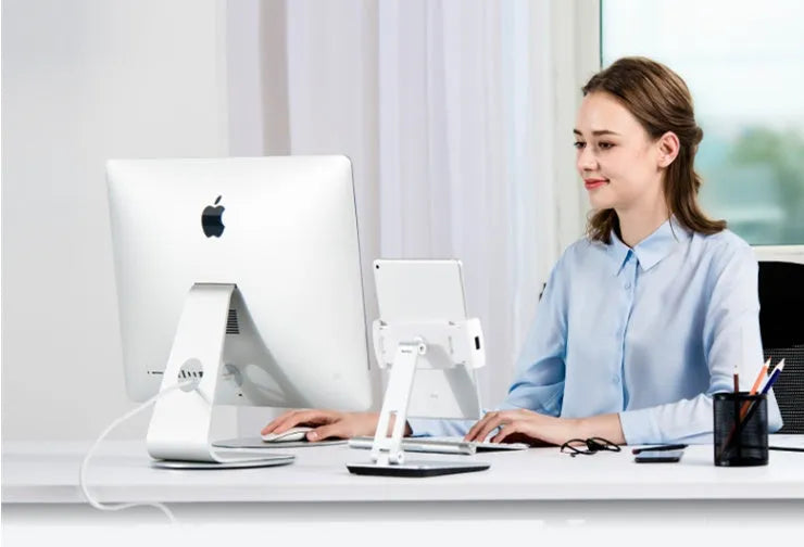 Black foldable aluminium phone and tablet stand with 360-degree rotation on a wooden desk
