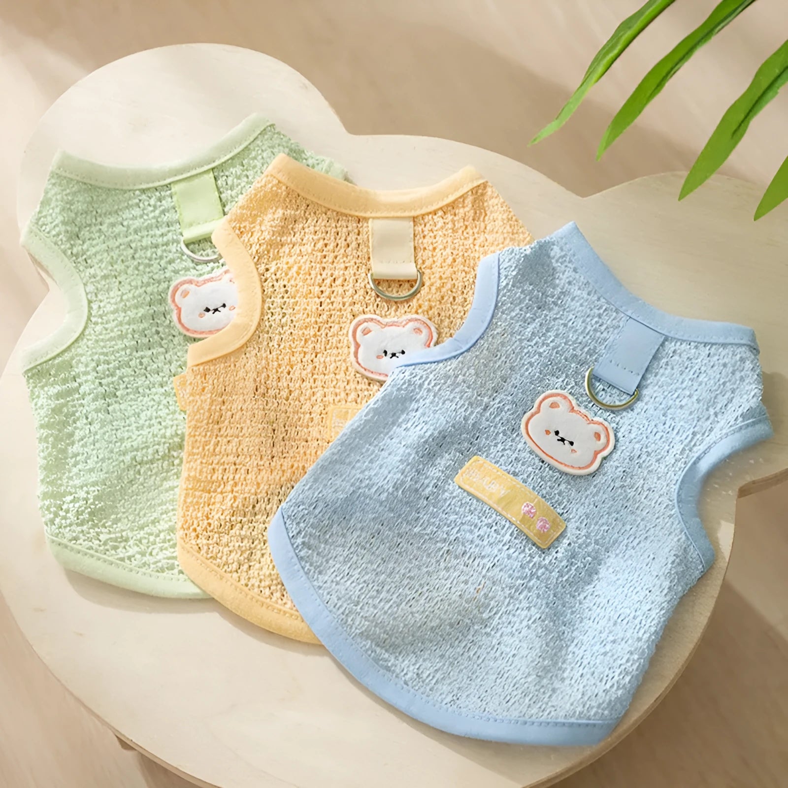 Green knitted cat clothing with a bear patch, showing hollowed-out breathable fabric.