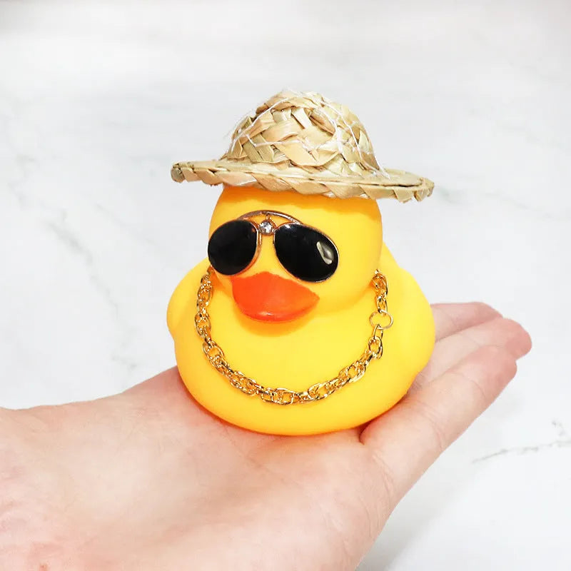 Cartoon yellow duck wearing a straw hat car dashboard ornament on a matte yellow base.