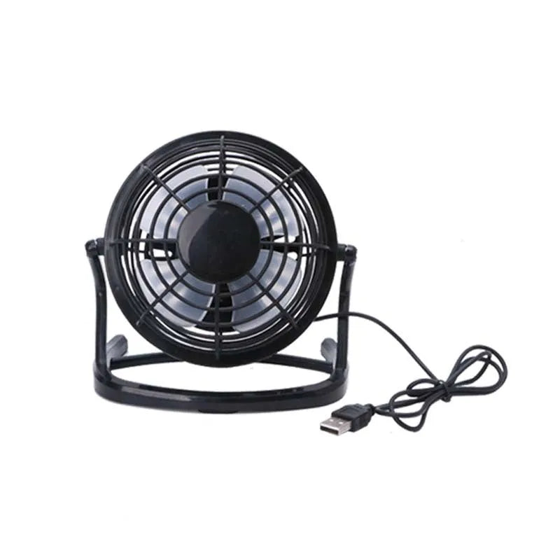 Compact black USB desk fan with adjustable tilt angle on a wooden desk next to a laptop