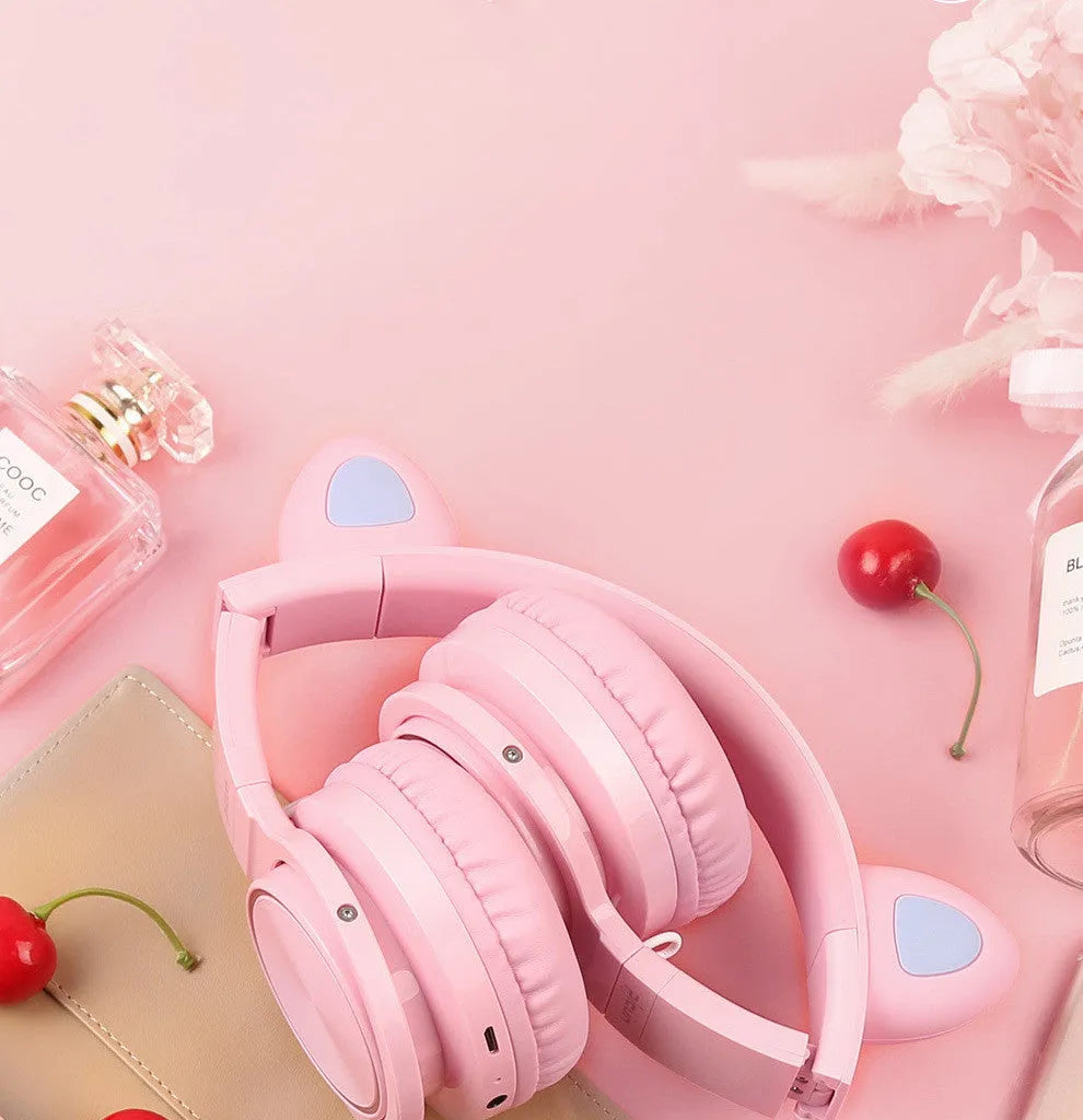 Pink and white wireless Bluetooth headphones with head-mounted design and braided cable