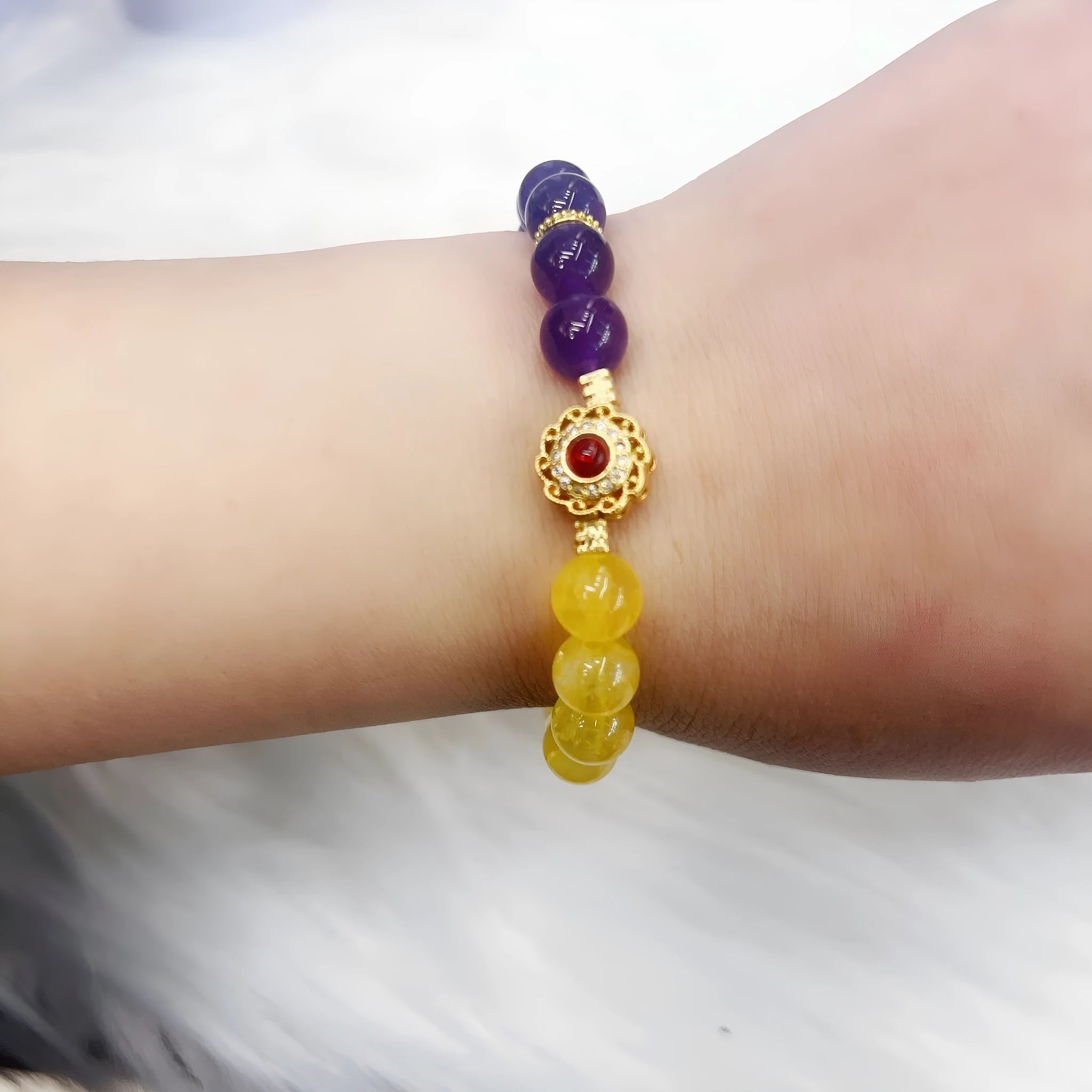 Handmade yellow and purple crystal women's bracelet on wrist.