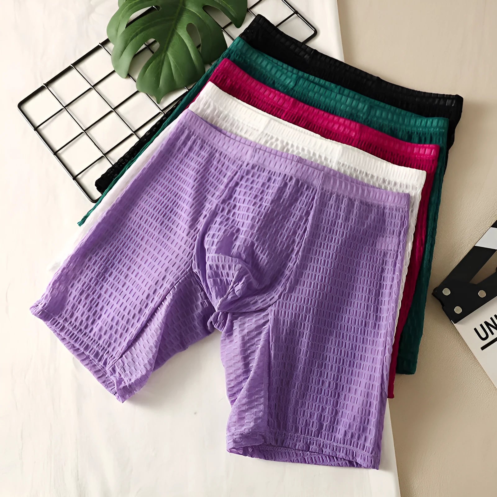 Men's lace boxer underwear in a lengthened hip lifting design on a solid colour background.