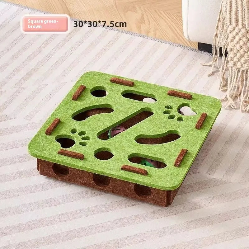 Rectangular green brown felt cat scratching box with holes, shown on a floor.