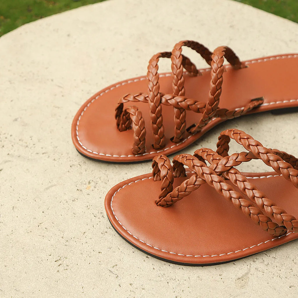 Women's flat woven sandals with clip-toe design in black, brown, and white on a rubber sole.