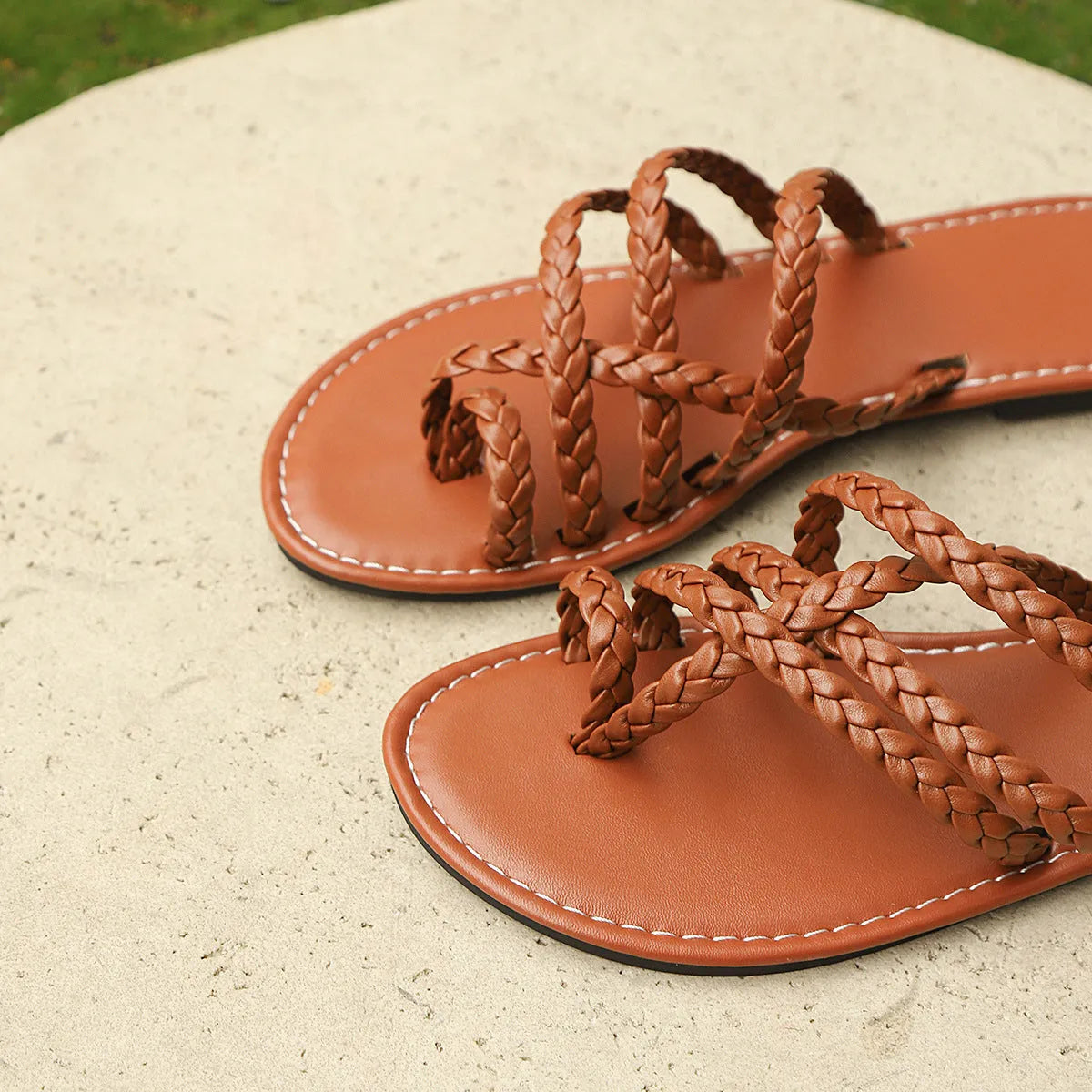 Women's flat woven sandals with clip-toe design in black, brown, and white on a rubber sole.