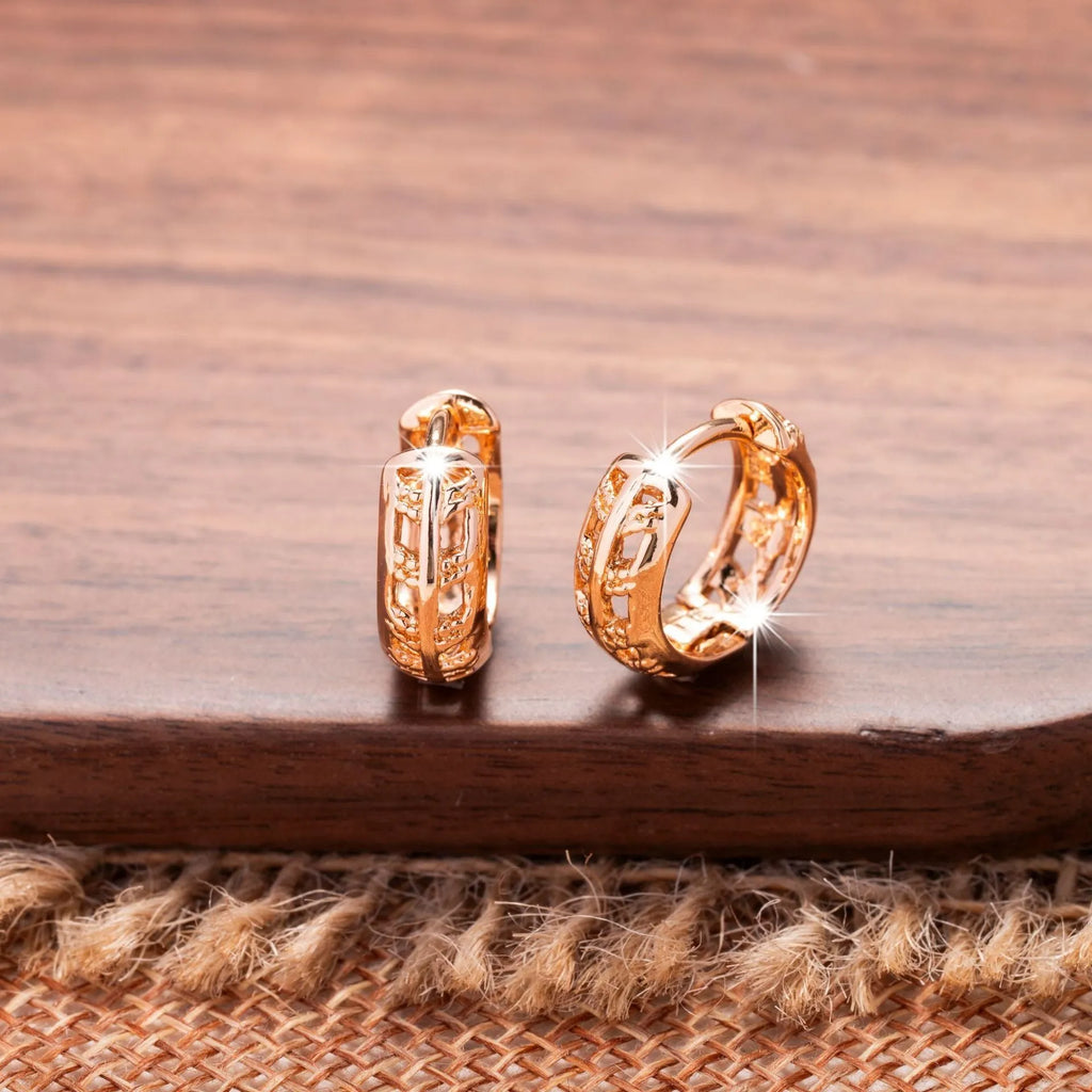 Rose gold coloured copper earrings with a hollowed leaf design and small heart detail.