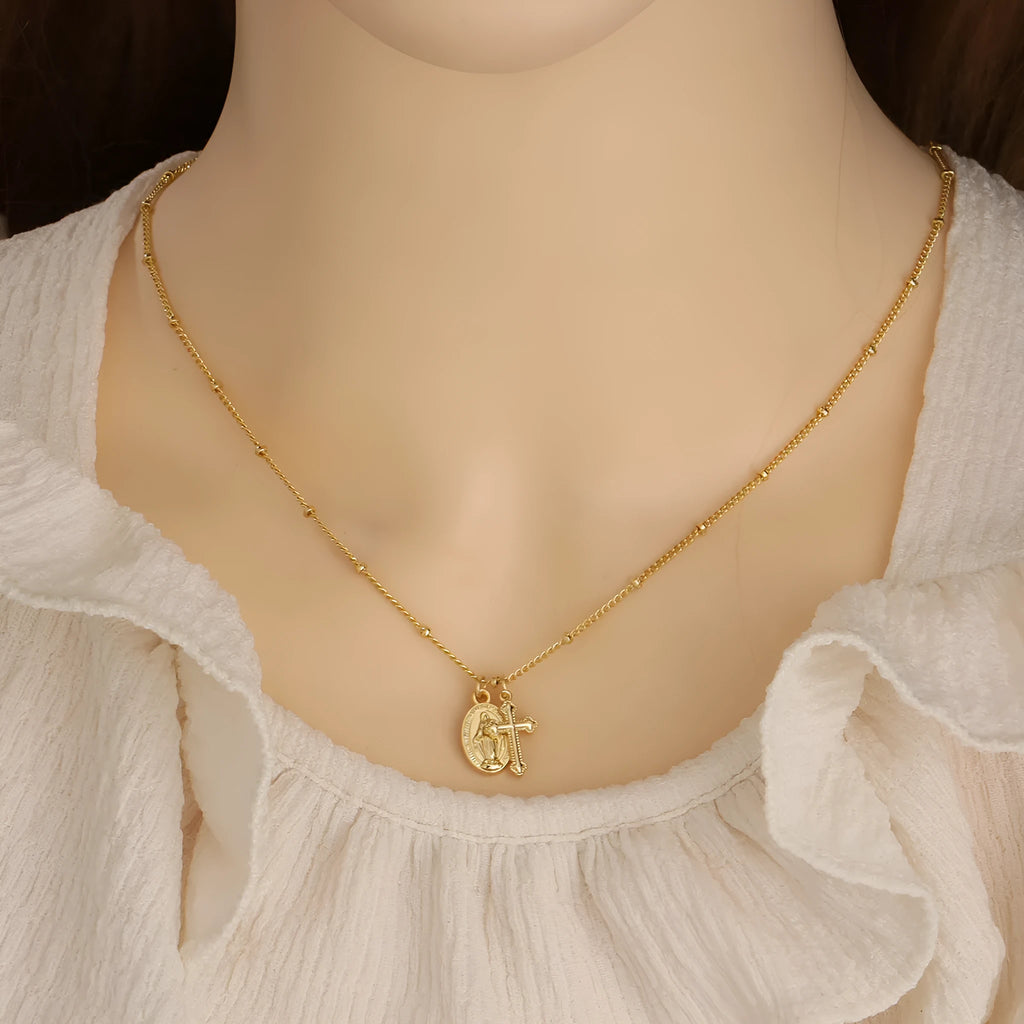 Gold geometric cross pendant necklace with Virgin Mary design on a chain.