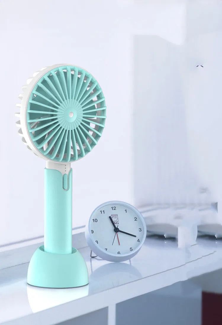 Blue mini handheld USB electric fan with three-speed control on a desk.
