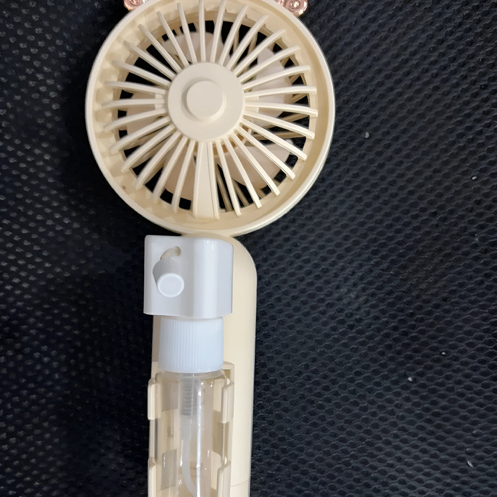 Compact plastic USB desktop fan with nozzle, shown in apricot colour, beside a USB cable on a desk.