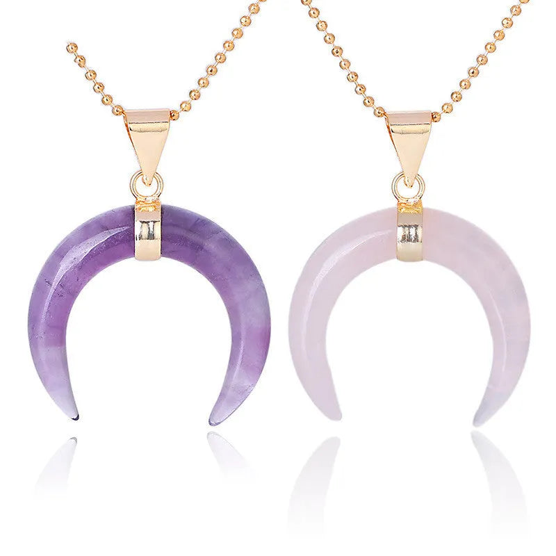 A pink semi-precious stone moon pendant on a copper-coloured chain, laid flat.