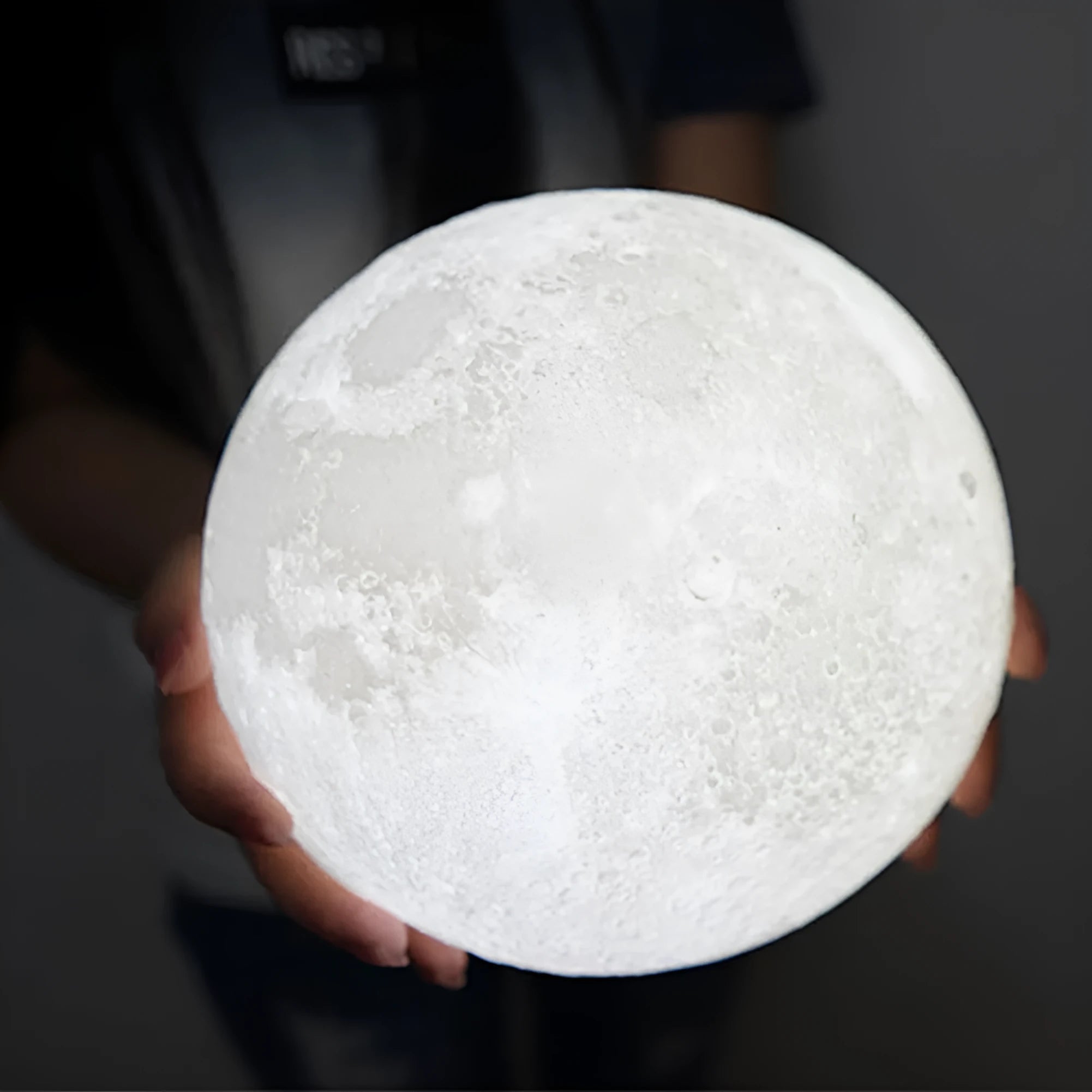 3D printed white moon lamp on a wooden stand, showing detailed craters and soft LED glow.