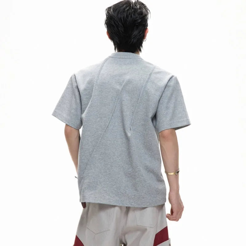 Men's loose grey cotton t-shirt with three-dimensional pleats and asymmetric stitching detail.