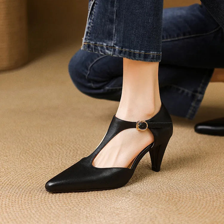 Brown retro women's T-strap sandals with a closed toe, low upper, and a stout high heel on a wooden floor.