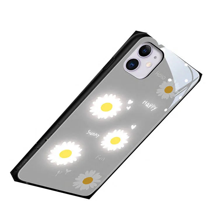 White and purple luminous iPhone cases with painted daisies and voice-activated colour lights on a table.
