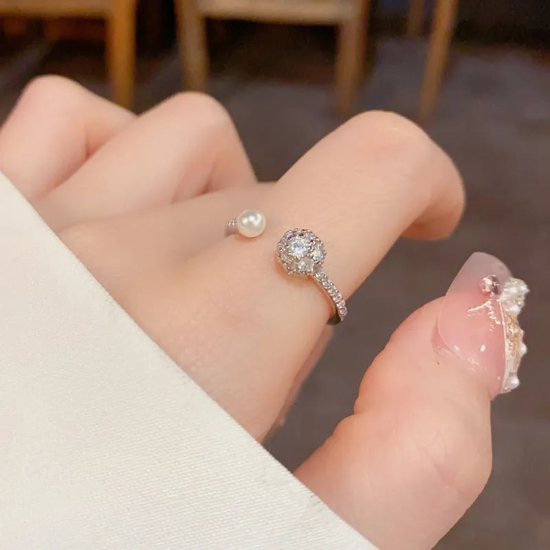 Open-end pearl ring with round zircon stones in gold plating on geometric copper base