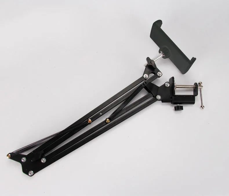 Black adjustable phone tablet stand with 360-degree rotation on wooden table