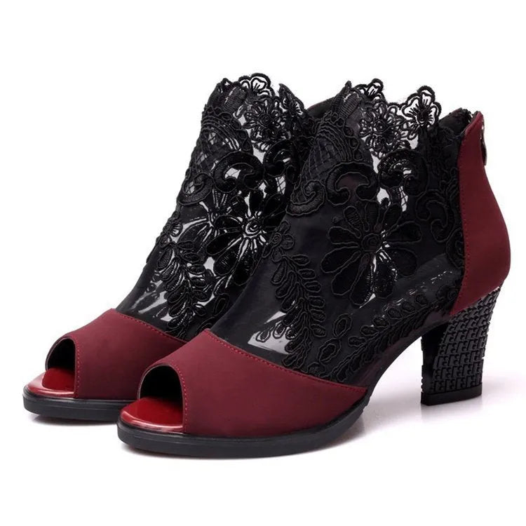 Black women's gladiator sandals with lace upper, square high heel, and side zip closure on a foot.