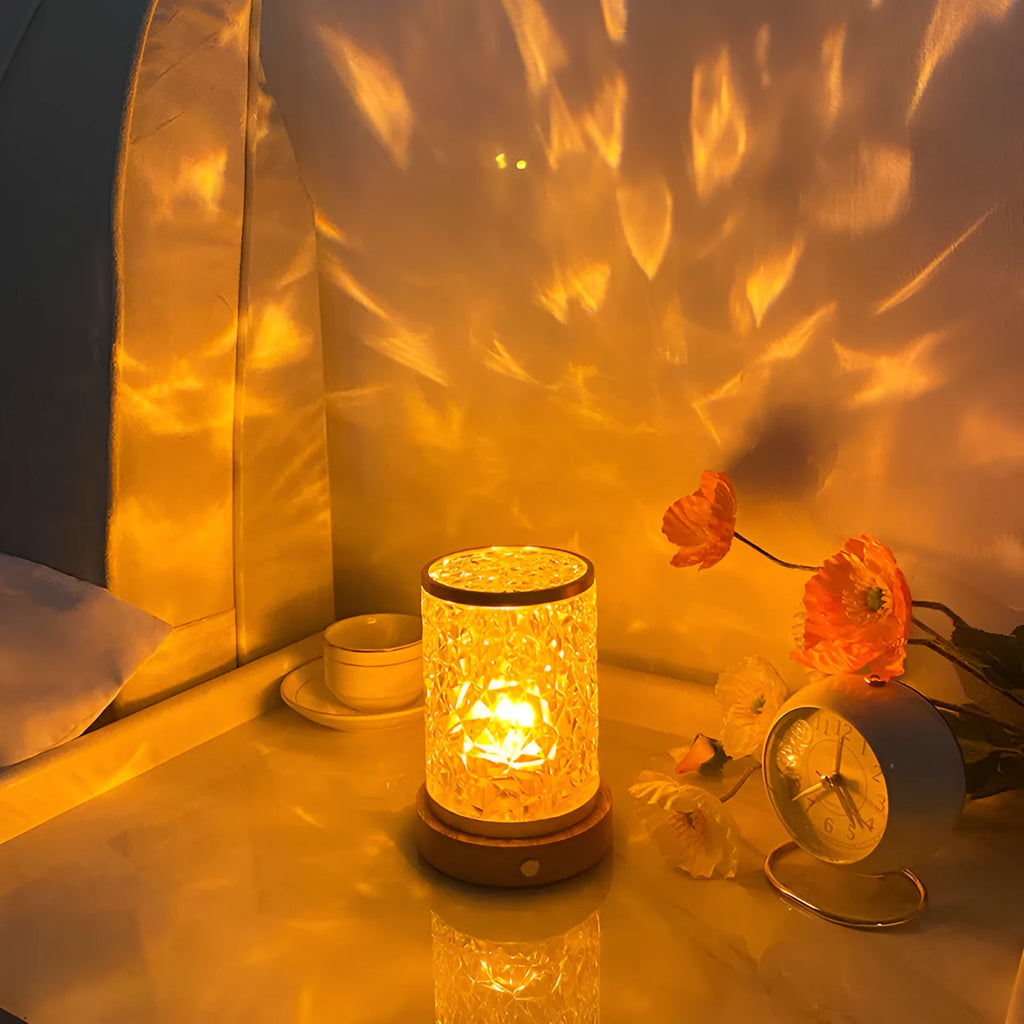 Rotating water ripple effect night light with acrylic body and solid wood base on a table.